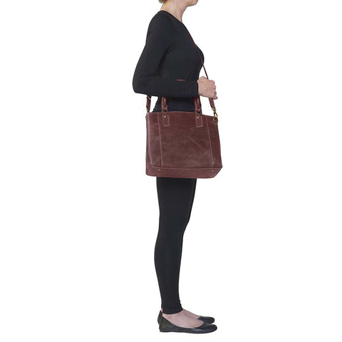 Bold distressed red full grain buffalo leather town tote with concealed carry functionality. Soft yet rugged vintage leather develops unique patina with everyday wear. Slash-resistant adjustable crossbody strap with padded gun compartment protects against imprinting. Designed for ambidextrous draw, multiple organizational pockets including secure zipper compartments. Includes Mernickle holster tested for compact and subcompact pistols. Perfect for confident, stylish concealed carry.