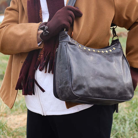 woman outside with a Slate gray concealed carry HOBO purse in soft vintage leather with dark chrome rivets, RFID protection, dual zip compartments, CCW access for Glock 26 or Sig P320, slash-proof shoulder strap, and left/right hand draw compatibility.