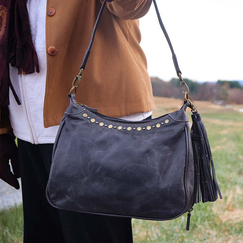 close up of a gray concealed carry HOBO purse in soft vintage leather with dark chrome rivets, RFID protection, dual zip compartments, CCW access for Glock 26 or Sig P320, slash-proof shoulder strap, and left/right hand draw compatibility.